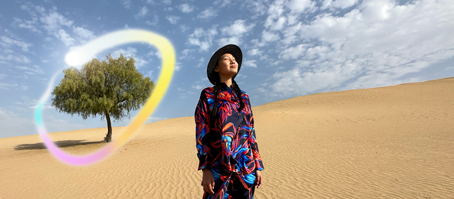 iPad Pro, écran face avant avec fond dégradé bleu foncé et vert et plusieurs apps ouvertes, main tenant un Apple Pencil Pro encerclant un croquis et illustrant la fonctionnalité baguette graphique d’Apple Intelligence