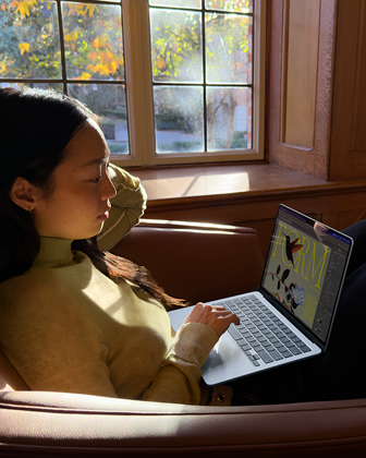 Une personne assise sur une chaise utilise son MacBook Air